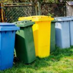 recycle bins for garbage on green grass near fence