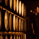 Female taster looking at the colour of whisky in glass at whisky distillery
